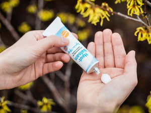 Aus der Tube wird Hautbalsam auf die Hand gedrückt